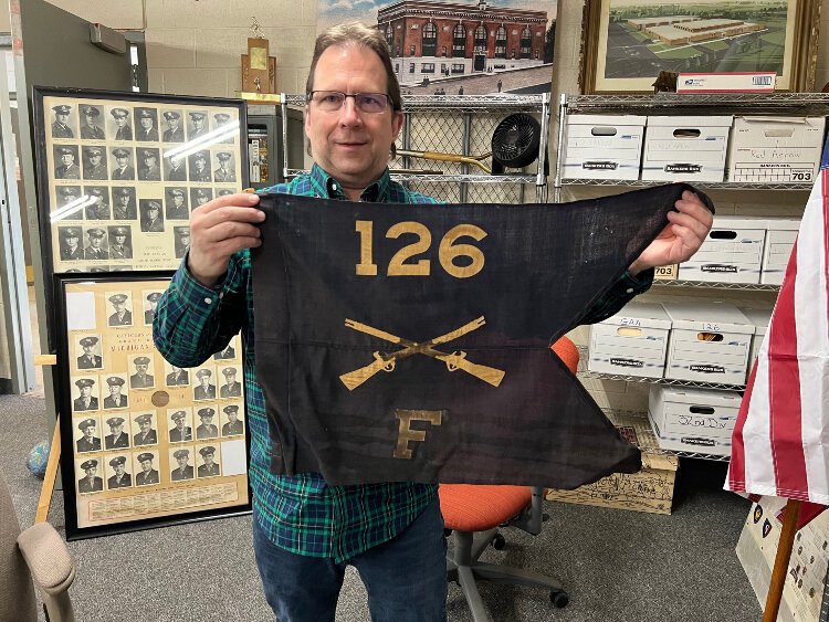 Historian Chris Petras holds up the guidon of the 126th Infantry/Regiment, WWI.