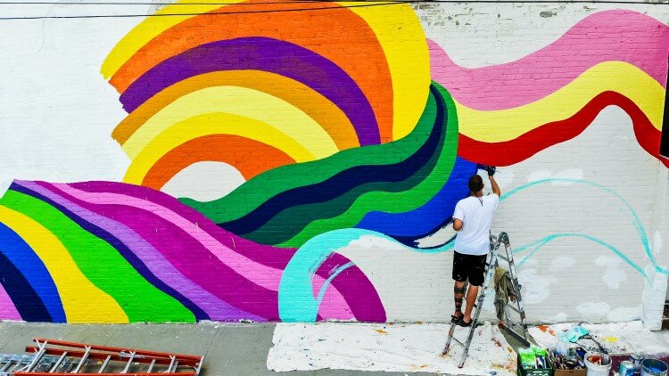 A new mural being painted on the exterior of Live Oak Coffeehouse is one of the many artistic additions.