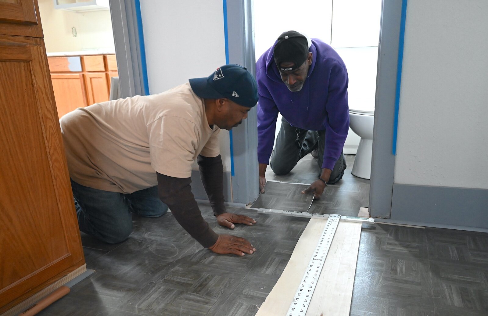 Robert Holley, left, and Aaron Cusic work on the flooring of the house at 238 Greenwood Avenue that Washington Heights United Methodist Church bought and is renovating.