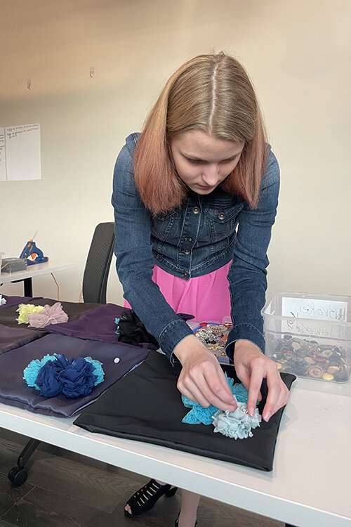 Abby Mitchell works on designing pillowcases made of materials from former dresses.