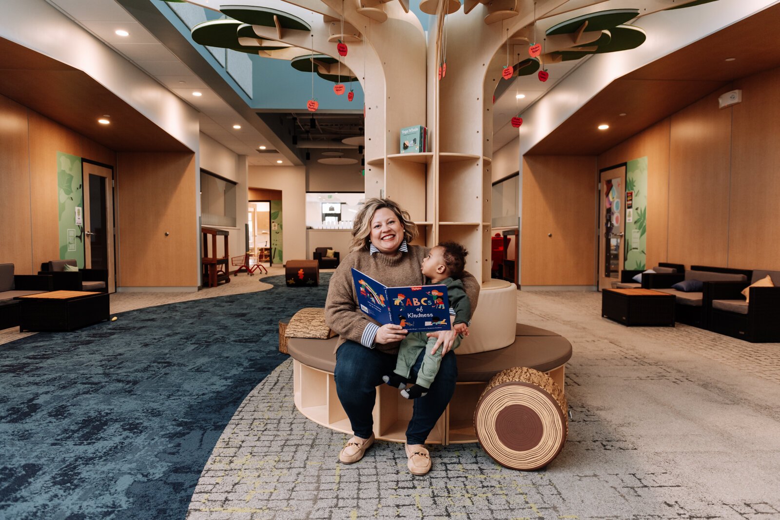 Kelli Packnett, Vice President of Education & Engagement, reads a book to Kaisen, 8 months, in the Ambassador Enterprises Park at the Bridge of Grace Early Years Academy.