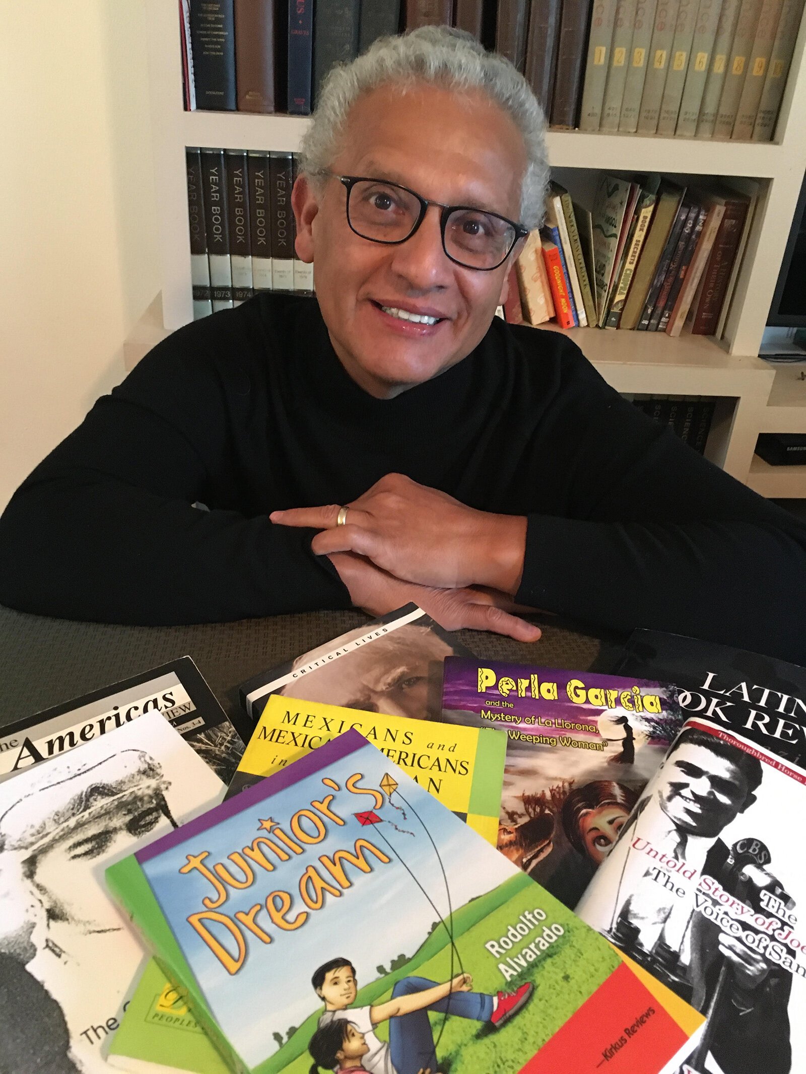 Rodolfo Alvarado with some of the books he's written.