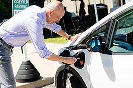 Richard Kosmacher, senior program director, Midwest, Mobility Development Operations, plugs in one of the electric vehicles at a launch event for a new electric vehicle car-share service available at Avalon Housing properties in Ann Arbor.
