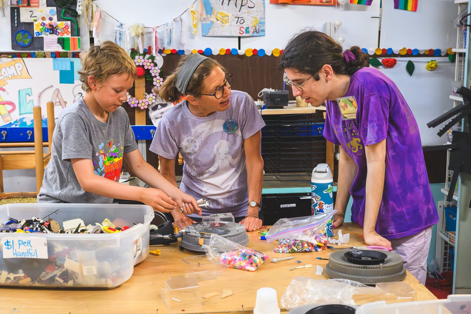 Mary Adams (center) and Jonathan Brant (right) help a child at Camp Scrap!