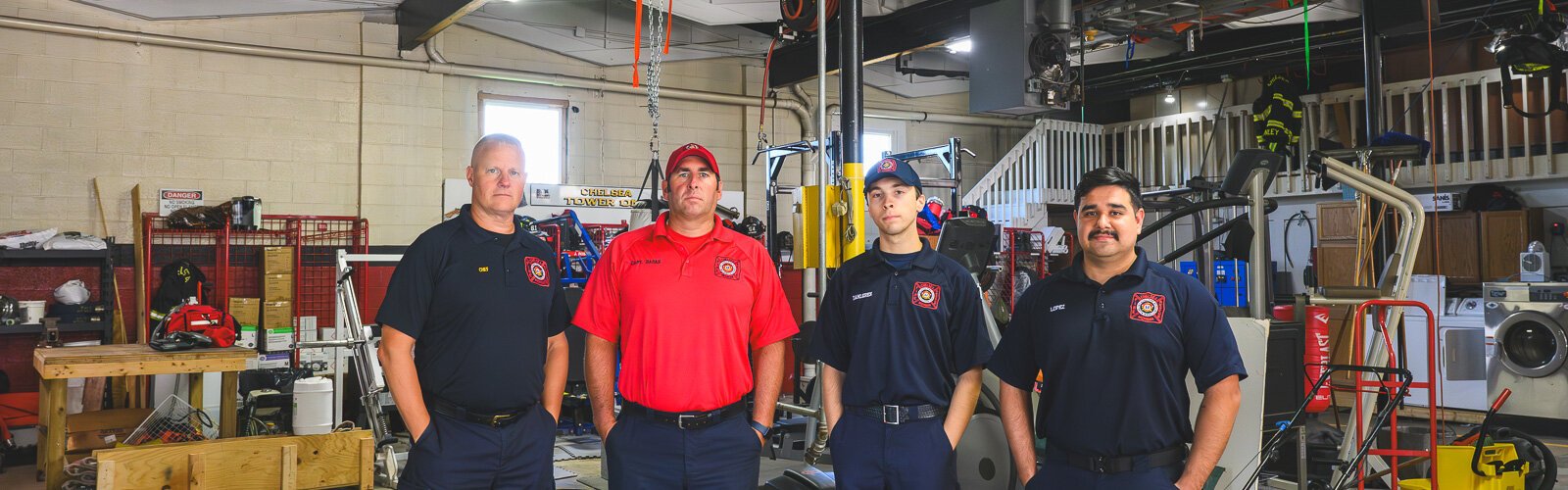 Chief Robert Arbini (left) with staff by the workout area in the bay of the Chelsea fire station.