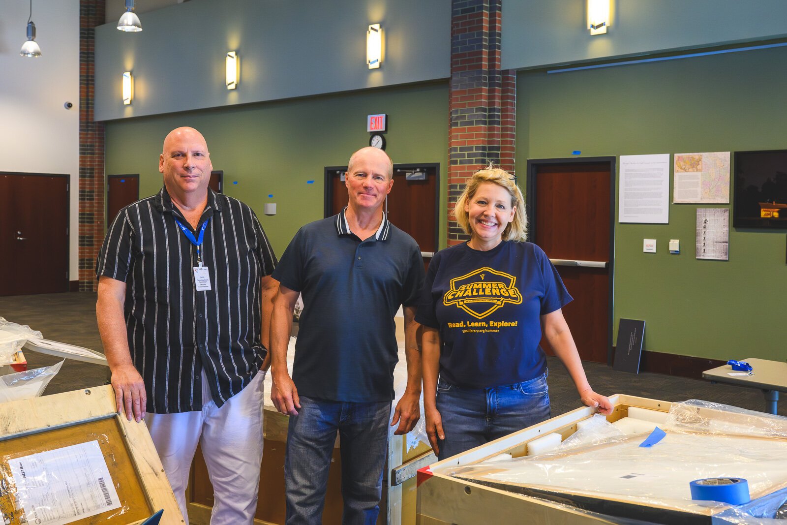 John Connaghan, Jim Reed, and Julianne Smith hanging the "Through Darkness to Light" Exhibit at the YDL Whittaker Branch