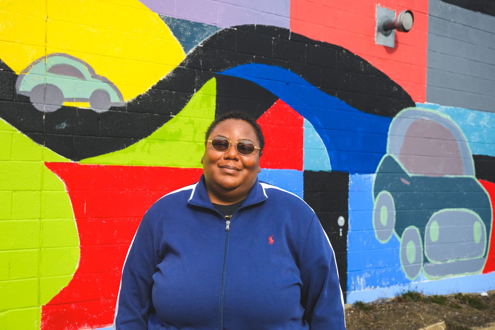 Youth Art Gallery Executive Director T'Onna Clemons in front of the Youth Art Gallery mural at Community Auto Wash.