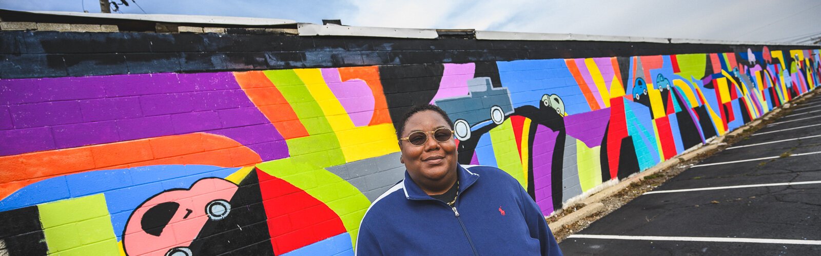 Youth Art Gallery Executive Director T'Onna Clemons in front of the Youth Art Gallery mural at Community Auto Wash.