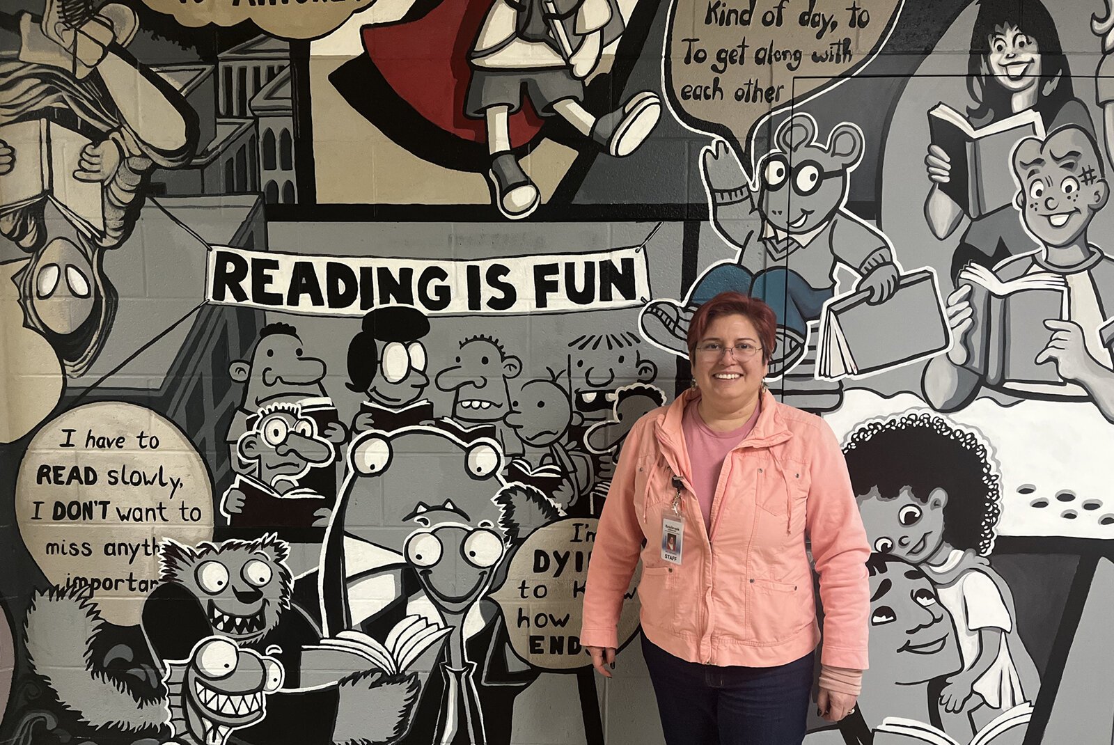 Stacy Schwartz stands in front of her mural, "Reading Can Take You Places," at Estabrook Elementary School.