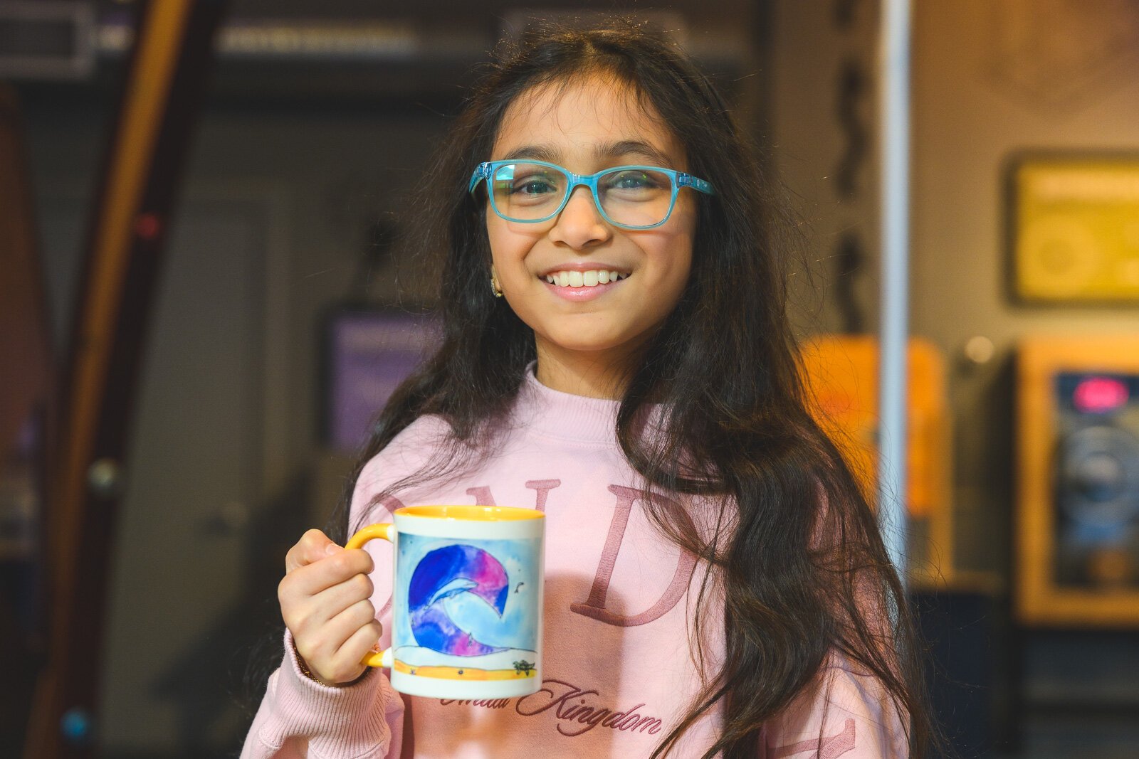 Doodles Academy past participant Swara Goyal holding a mug with her artwork that she was awarded.