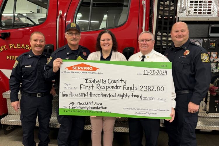 Brittany Smith (center) stands with the Mt. Pleasant Fire Department with a donation to the Isabella County First Responder Fund.