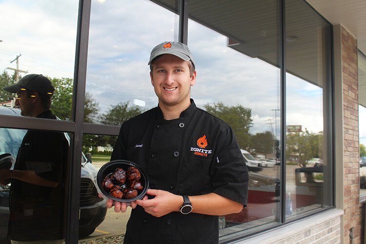 Founder and CEO, Casey Croad, with a selection of Ignite Donuts topped with a chocolate glaze.