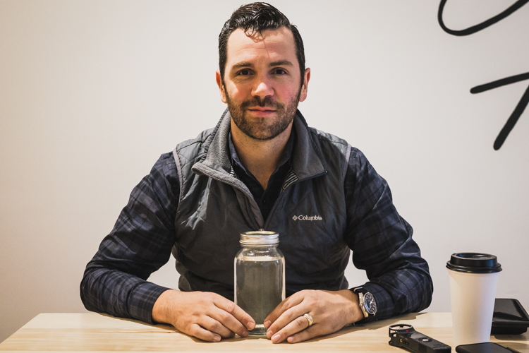 Mike Schuette of GCI water with a jar of clean, treated water