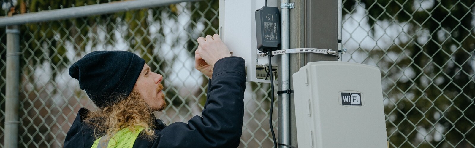 Nate Rauh-Bieri with JustAir checks on an air quality monitor with a color-coded light: “At a glance, residents can have a sense of how the air is that day in that space.” 