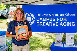 Amy Nichols, campus coordinator for the Region IV Area Agency on Aging, at the Campus for Creative Aging's booth in the South Haven Art Fair. She shows an example of the Window to Our World art project for care partners.