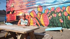 Neighborhood Connector Lori Appeldoorn pauses at one of many welcoming stops along Central Avenue. This one, in front of JJ's on the corner of Central and 16th Street, includes yard games, lighting, and picnic benches for neighborhood gatherings.