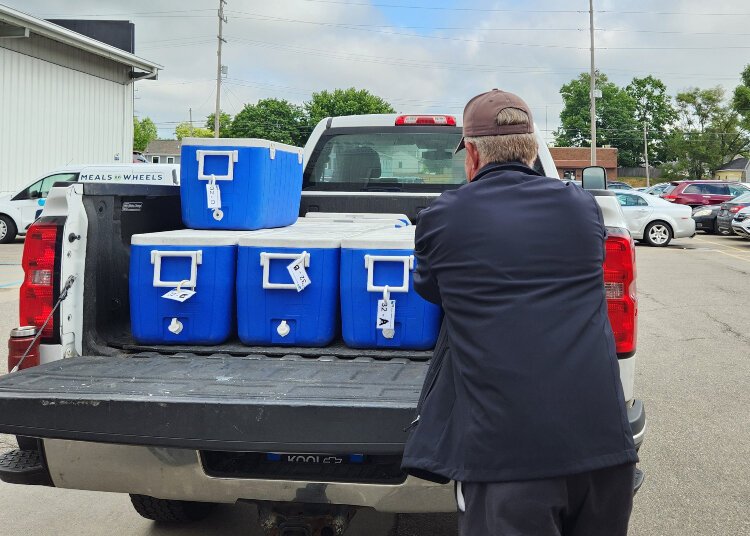 A volunteer loads coolers into his truck, preparing for meal deliveries.