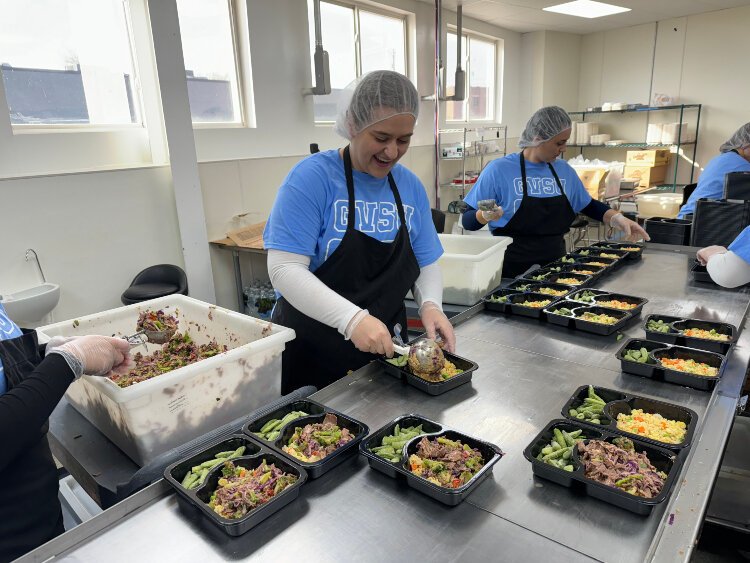 A group of volunteers carefully plate Meals on Wheels Western Michigan's Beef & Broccoli meal, featured in the Fall Choice menu.