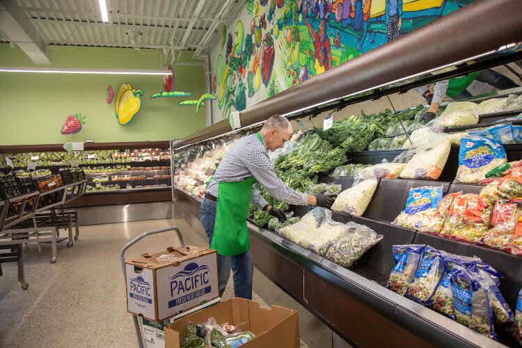 A volunteer helps stock the shelves at the Community Action House Food Club.