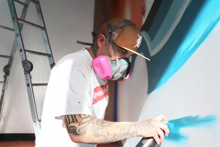 Muralist Chris Garcia paints Waves of Innovation on Lakeshore Advantage's newly built Next Center in downtown Holland.