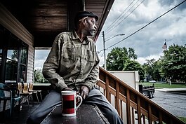 A stand member looks out across the neighborhood from the Porch of The Lemonade Stand of Muskegon.