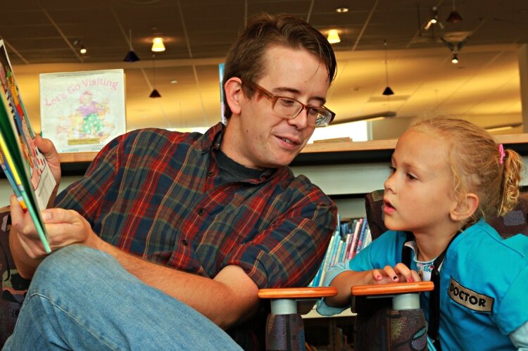 A father reads to his daughter at Herrick District Library.