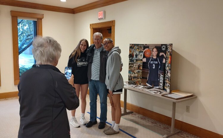 West Ottawa basketball players Taylor Catton, left, and Gabby Reynolds, right, have their photo taken with a fan following a Q&A session at Evergreen Commons.