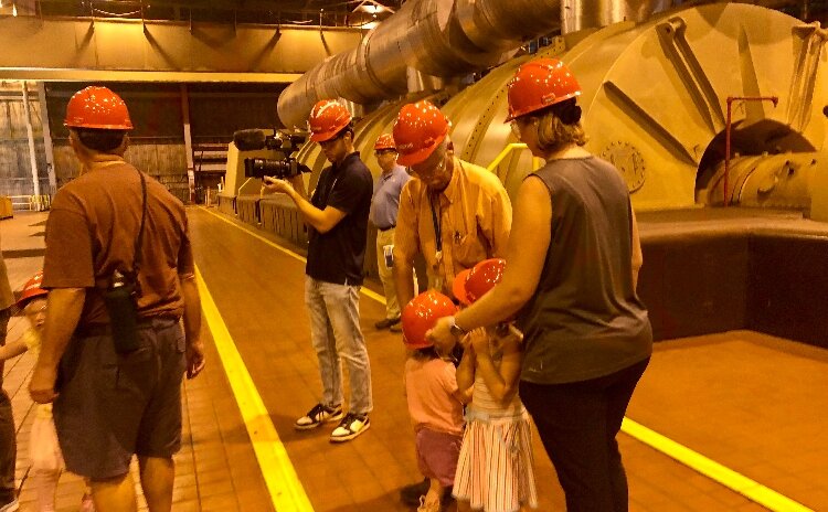 Stephanie Aubin of Holland (right), accompanied by her father John Garrod (yellow shirt), shows her daughters Amelia, 5, and Ellie, 2, one of the huge turbines gearing power at the J.H. Campbell complex.