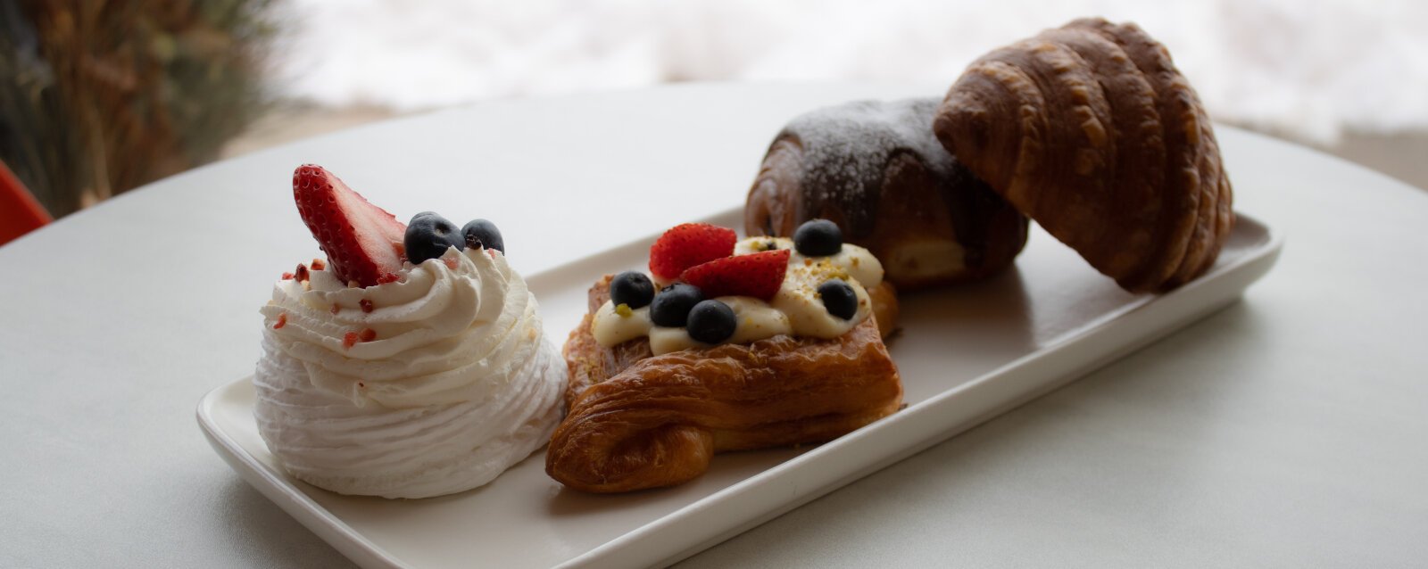 A Pavlova, Danish and Croissants on a serving plate from Chef Sergey’s Bakery