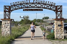Jackie Hanton, vice president of the Community Foundation of St. Clair County, running with her daughter Kennedy underneath the Blue Water River Walk archway.