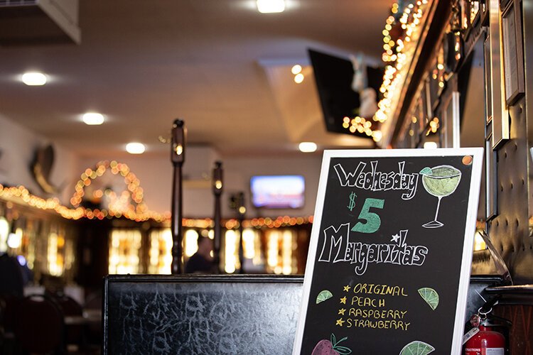 A sign displaying daily specials greets guests coming through the back entrance of the Brass Rail Bar.