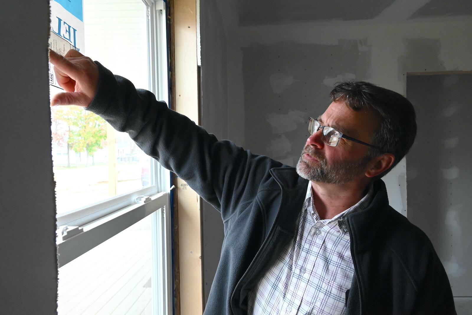 Mike King, executive director of the Battle Creek Area Habitat for Humanity, points out the efficiency rating of a window at a house under construction.