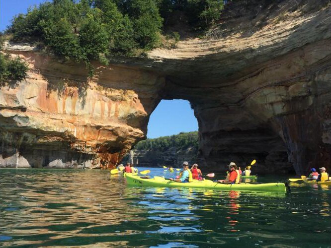 Kayakers paddling along the rocky coast of Pictured Rocks National Lakeshore.