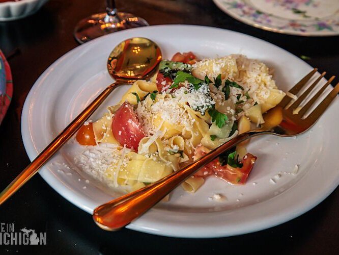 Homemade tagliatelle with local tomatoes, garlic, and parmesan, garnished with fresh basil.