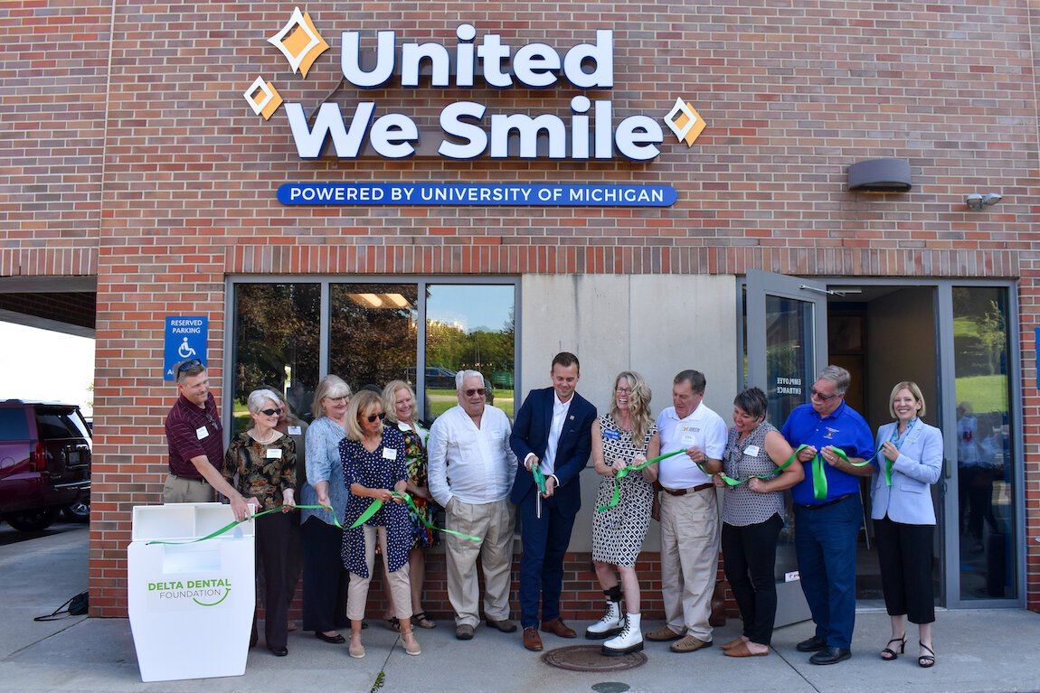 The United We Smile team celebrates together as they "cut the floss" to mark the clinic's grand opening in Traverse City.