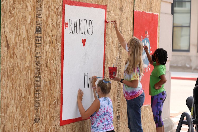 Kanley Couvault, Mandy Clearwaters, and Jasmine Waters paint boarded windows downtown earlier this year. 