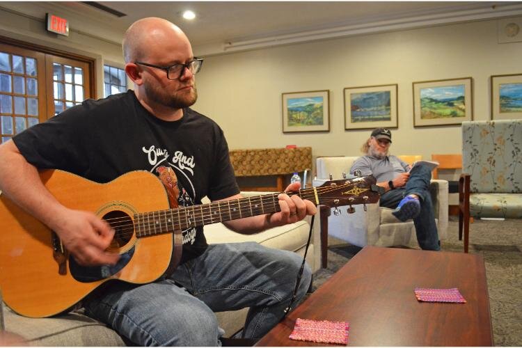 Johnson plays his guitar for the group during the beginning of the meeting.