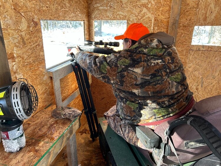 A guest at Hunt 2 Heal takes aim from a hunting blind. 