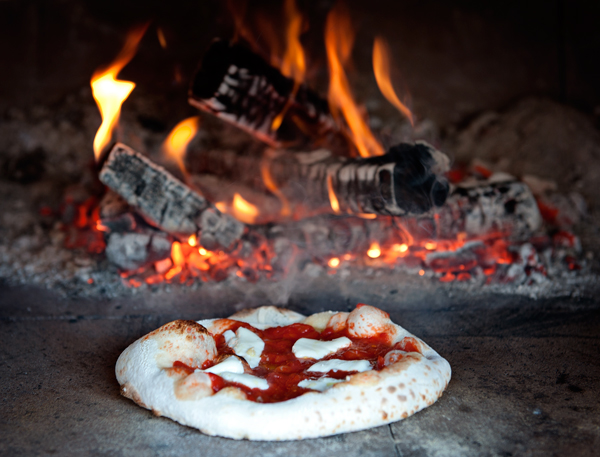 A margherita pizza bakes in the Pizza Vera wood burning oven. 