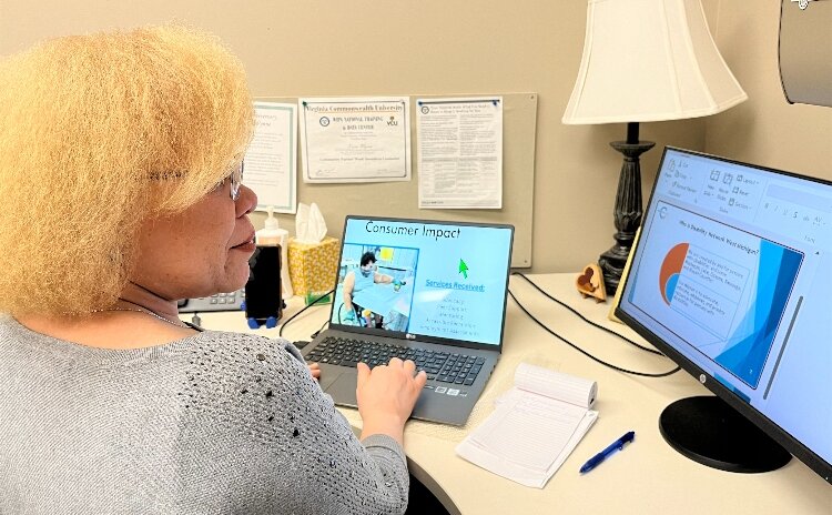 Karen Wynne, a Benefits Planning Specialist with DNWM, is seated at her desk in an office, working on a presentation.