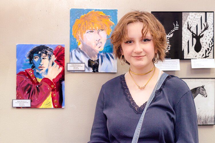 Anna Schulio, a student at Calhoun Christian, stands by her portraits.