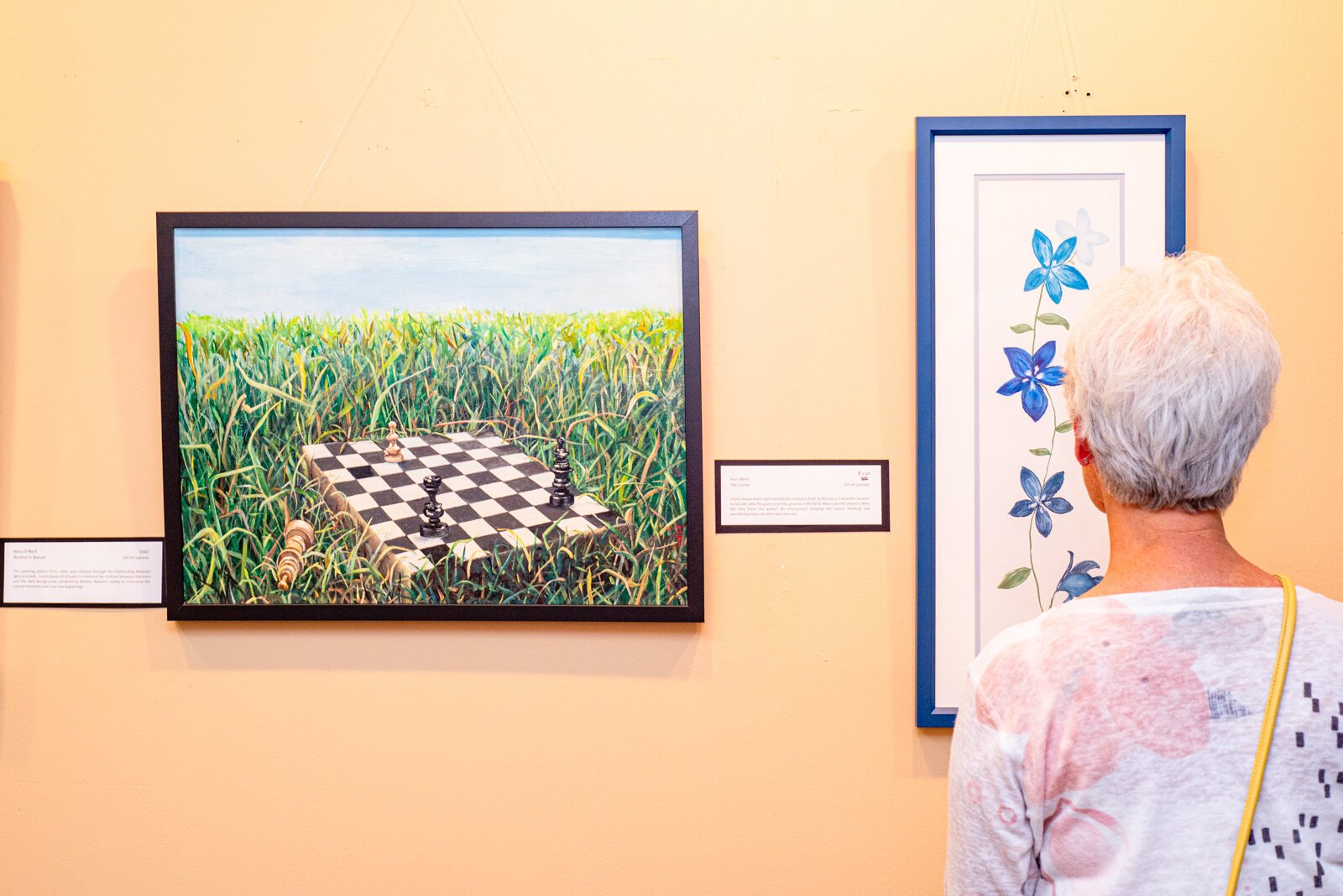 Patron Admiring Jean Weir's "The Game" and Renée Szostek's "Floral Friends in Blue."