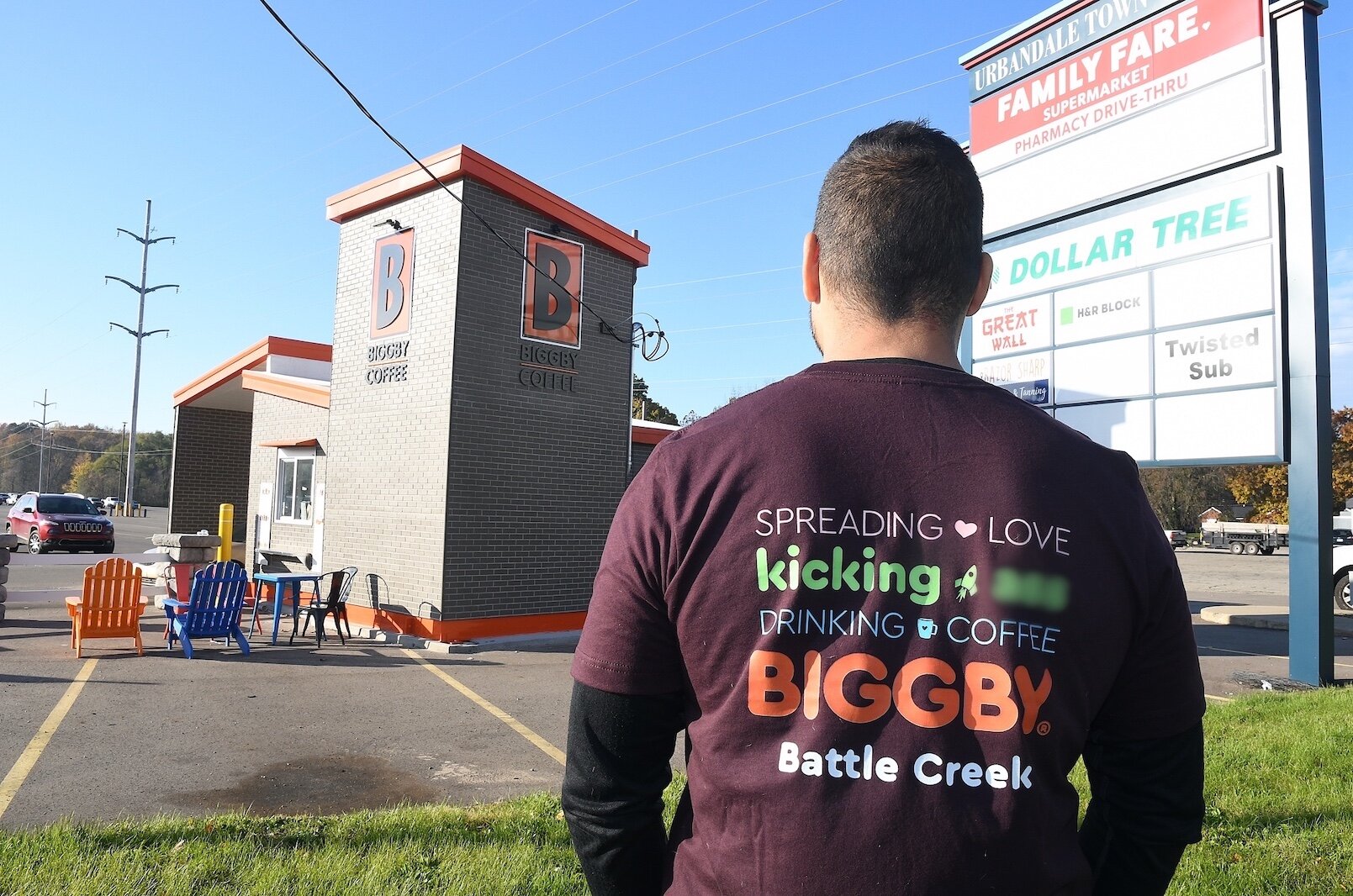 Wearing a shirt designed by his staff Charles Solano stands near the newly drive-up only Biggby Coffee shop on West Michigan Avenue in Urbandale.