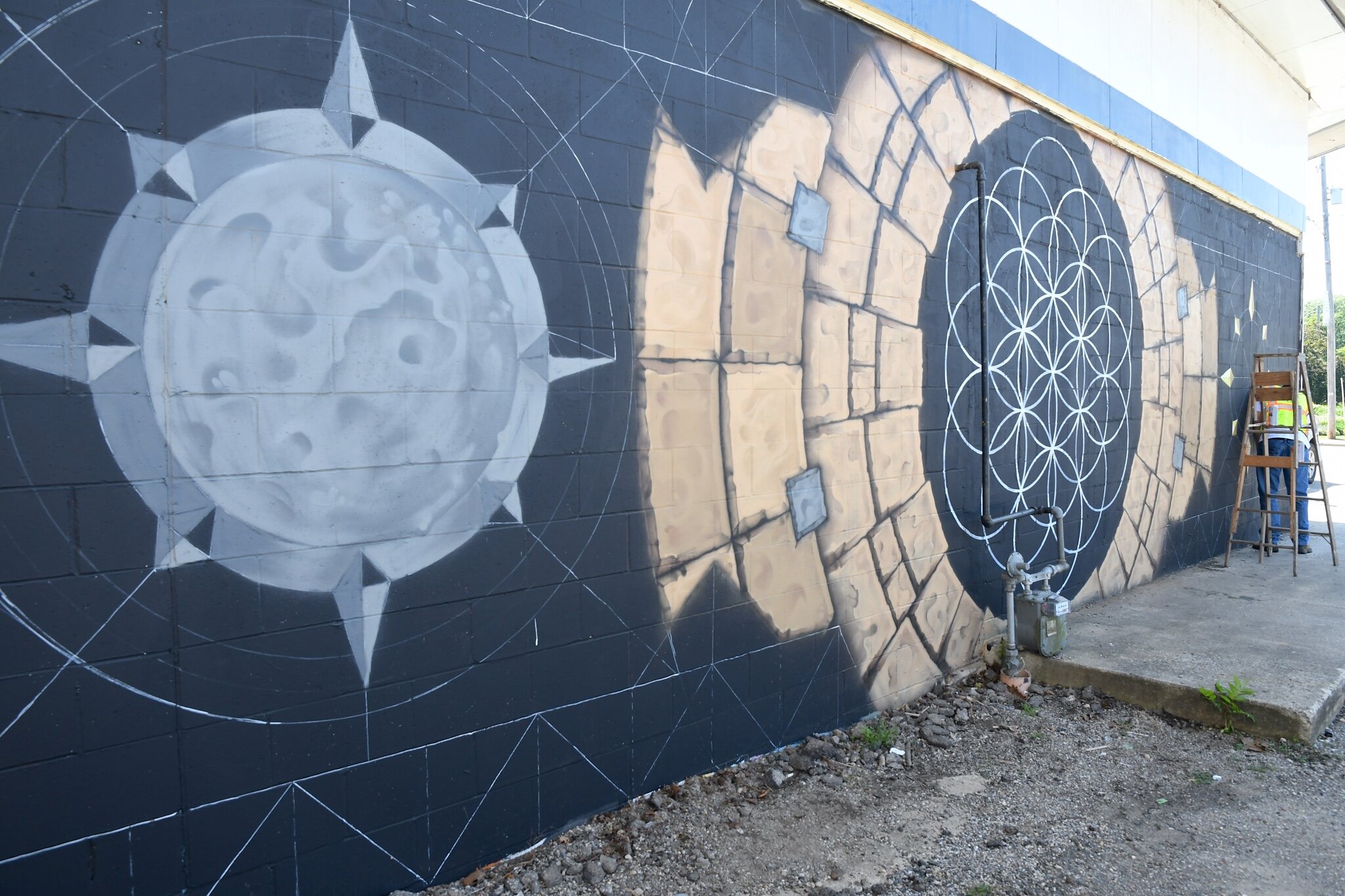 Jars of Battle Creek works on mural on a wall of K and A Food Mart on Calhoun Street.