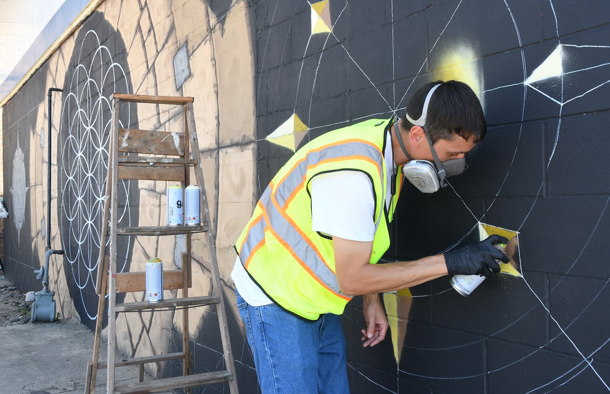 Jars of Battle Creek works on mural on a wall of K and A Food Mart on Calhoun Street.