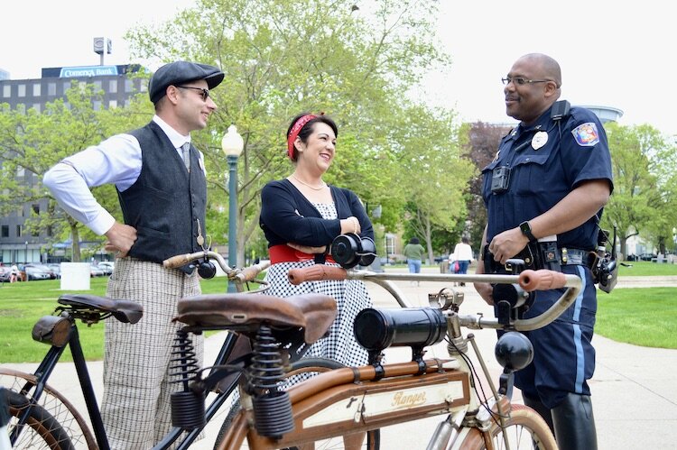 Cory Playford and Stacy Yates Droski of C.P. Cycle and Sundries talk antique bikes with Kalamazoo Public Safety Captain Christopher Franks.