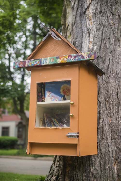 This Little Free Library has a charming Vine-ish twist with its bright orange paint and attached to a tree.