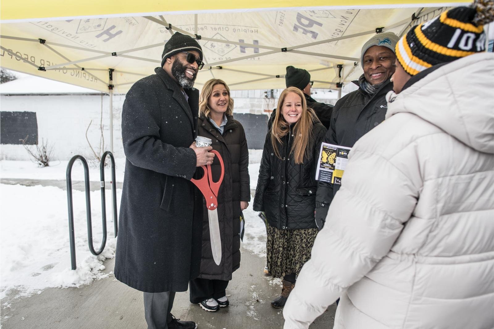 Kevin Crittenden, with scissors, was among staff members of Southwest Michigan First to attend the Dec. 12, 2024 open house of the HOPE Thru Navigation tiny houses.