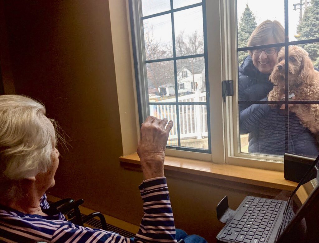 A woman brings a pet dog to to do a “window visit” with a resident of one of the Heritage Community’s facilities.