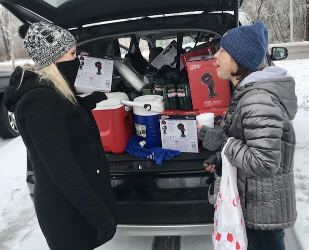 Two women talk on a recent Saturday afternoon as volunteers with the Kalamazoo Coalition for the Homeless prepare to hand out portable propane heaters to people at homeless encampments in downtown Kalamazoo.